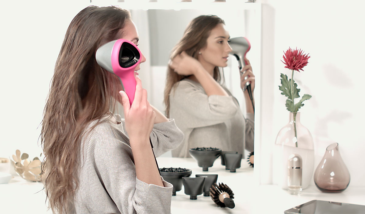 Mujer mirando su cabello brillante y ondulado frente al espejo
