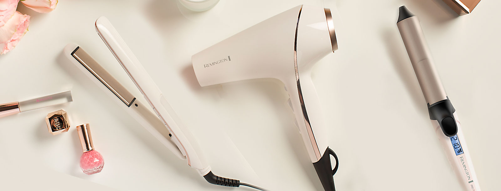 Secador, plancha alisadora de cabello y rizador en fondo color crema.