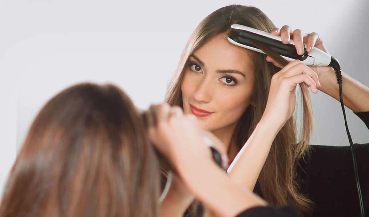 Mujer alisando su cabello con plancha de placas flotantes fácil de usar